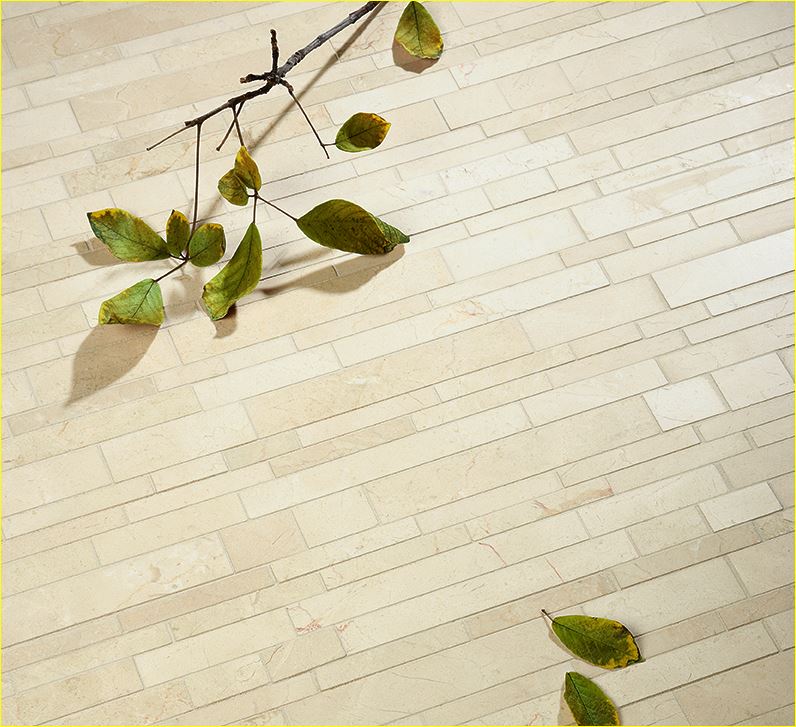 Beige stacked stone wall with slim rectangular tiles and scattered leaves