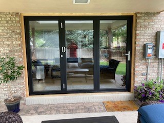 Large black‑framed sliding glass door opening a living room to the outdoor porch
