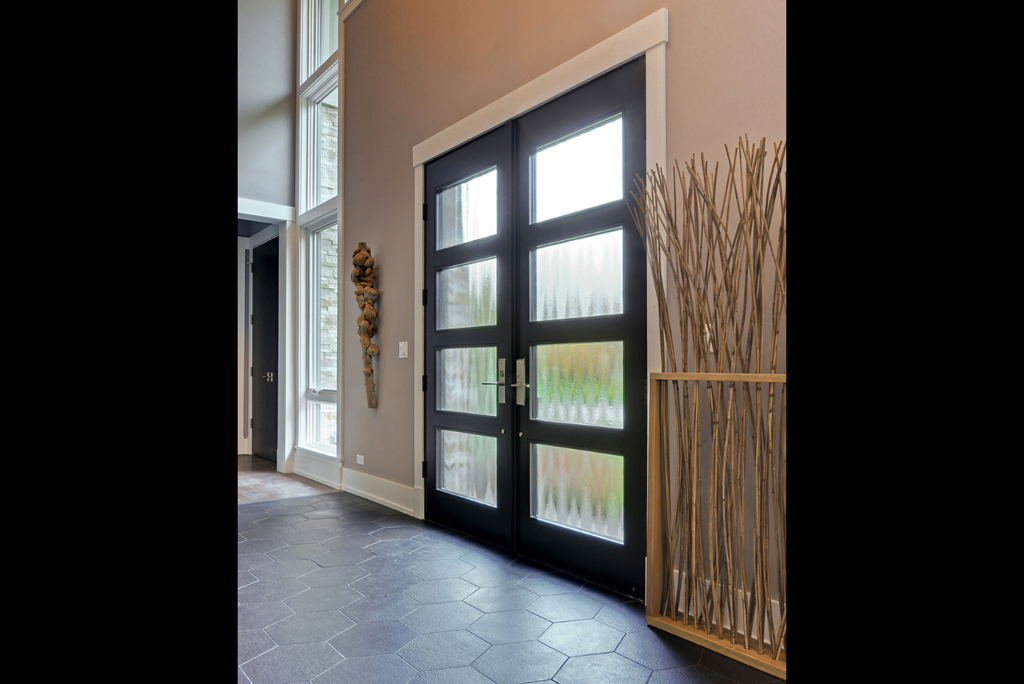 Modern black exterior door with slim vertical glass insert set in minimalist facade