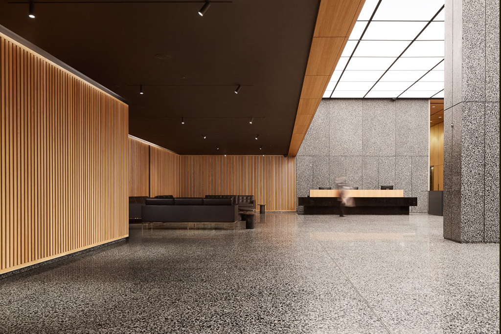 Spacious modern lobby featuring wood paneling, terrazzo floors, and a reception desk