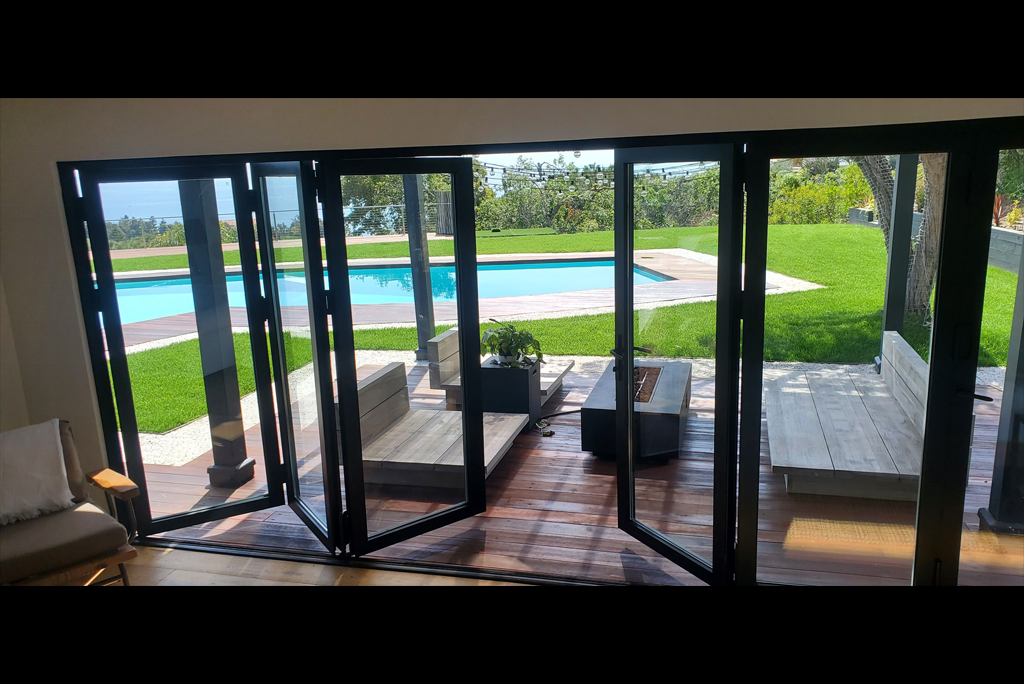 Contemporary lounge with sleek furniture facing tall bifold glass doors to the garden and pool.