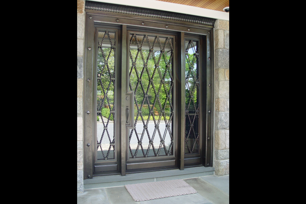 Matte black double main door in steel with staggered rectangular slots and minimalist handles.