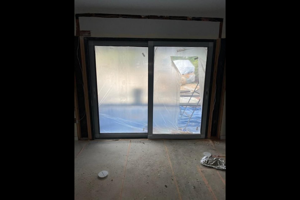 Newly fitted sliding glass patio door in an under-construction living room.