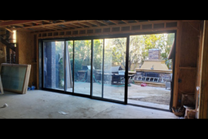 Floor-to-ceiling sliding glass door system framed in timber during construction.