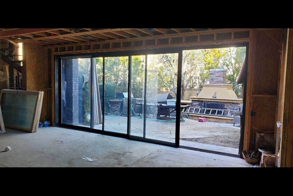 Floor-to-ceiling sliding glass door system framed in timber during construction.