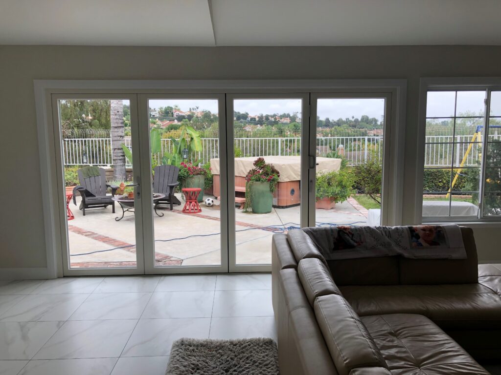 White bi-fold doors opening to a patio with Buddha statue