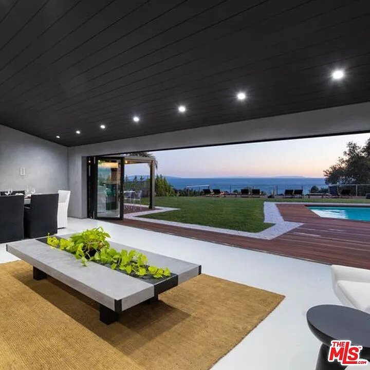 Modern living room with open glass doors to pool and garden